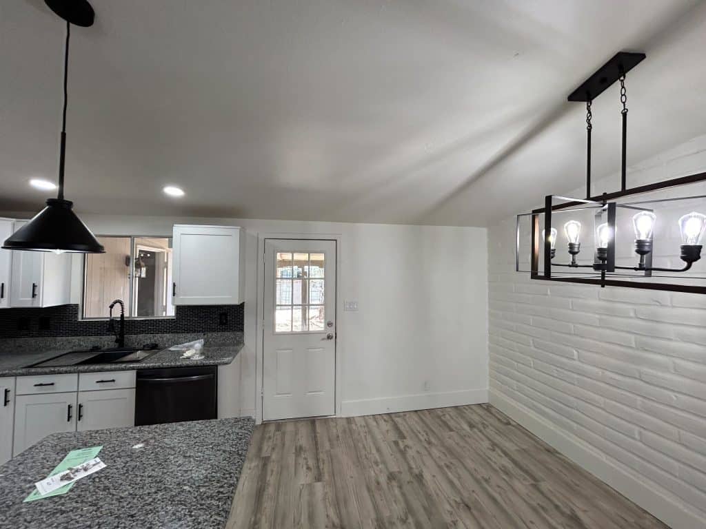 Remodeled interior featuring white cabinets, black fixtures, and open concept dining area – Kat Remodeling project