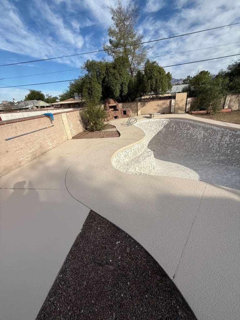 Resurfaced pool deck with clean textured concrete finish with updated decking and landscaping by Kat Remodeling in Tucson, Arizona