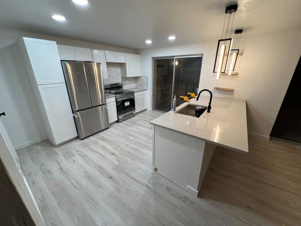 Sleek kitchen upgrade with waterfall counter, subway tile backsplash, and custom lighting by Kat Remodeling